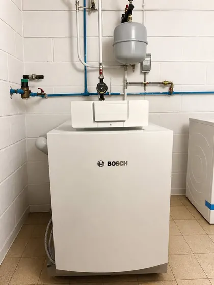 Chaudière Bosch posée au sol dans une chaufferie, avec son vase d’expansion et ses raccordements en cuivre.