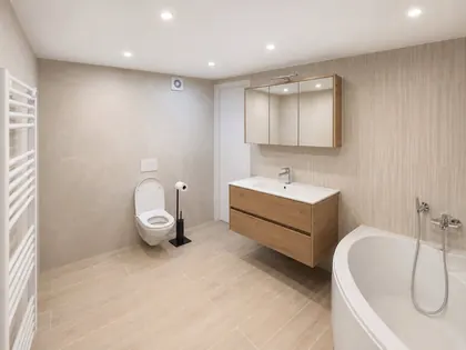 Salle de bain terminée : meuble en chêne, WC suspendu et baignoire d’angle.